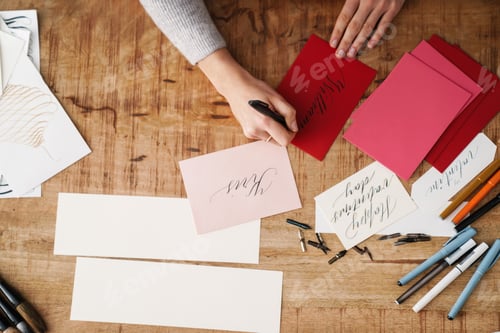 Preview: Calligrapher girl writing while working on valentines at table indoors
