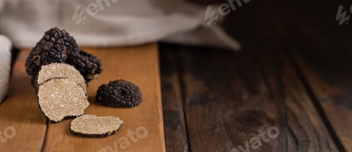 Preview: Whole and sliced black truffles mushroom on wooden board on dark brown table, close up