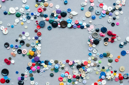 Preview: top view of colorful buttons frame on grey cloth background