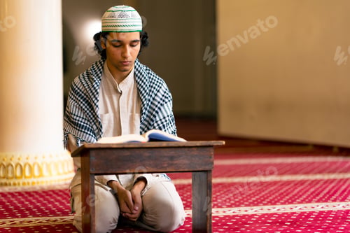 Preview: A Muslim man sits in silence on the carpet in holy mosque prays reads the Koran and turns to Allah