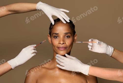 Preview: Attractive black middle aged woman getting cosmetic injection in her face, four hands of two