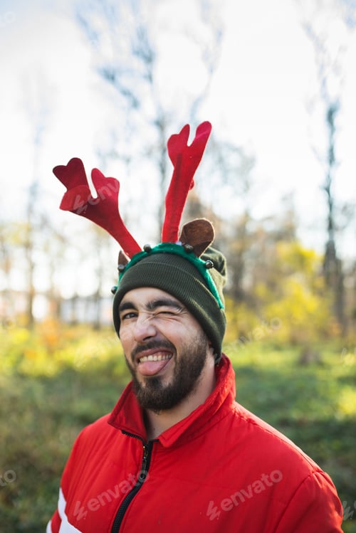 Preview: Man with festive antlers and deer ears smiles. Christmas mood. Deers antlers. Costume. Happy.