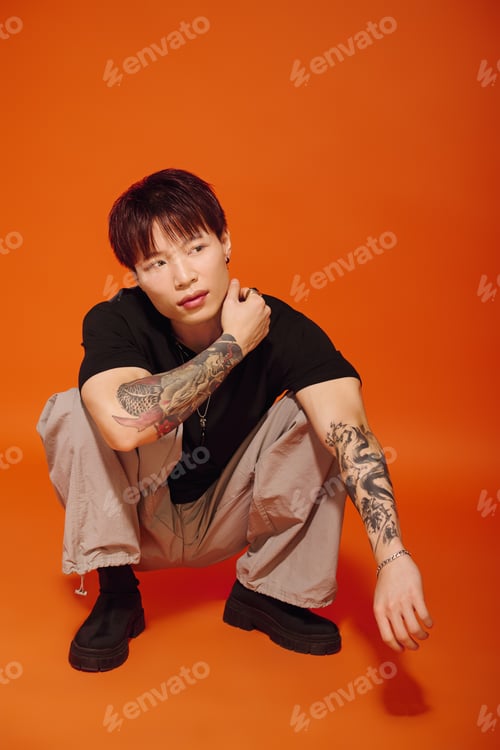 Preview: Stylish young man poses confidently against an eye catching orange backdrop