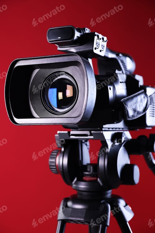 Preview: Modern video camera on red background, closeup