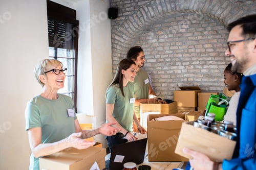 Preview: Group of volunteers with face mask working in community charity donation center.