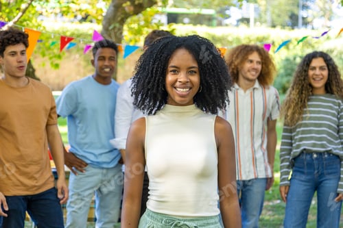 Preview: A smiling young woman stands in focus at the front while her friends gather behind her outdoors.