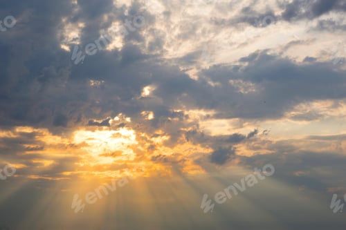 Preview: Orange rays of the sun through cumulus clouds in the sky at sunset in summer. Heavenly magic light.