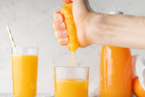 Preview: person squeeze fresh orange juice with a bare hand, healthy drink in a glasss
