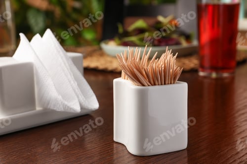 Preview: Holder with many toothpicks on wooden table, closeup. Space for text