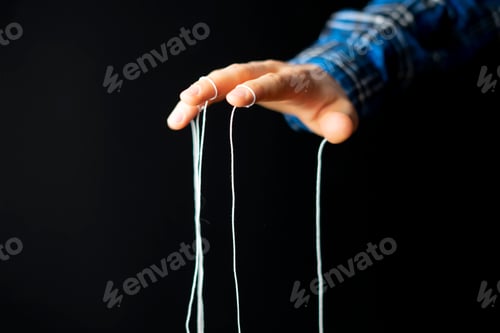 Preview: a puppeteer's hand with ropes on fingers control the people mind concept