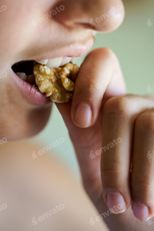 Preview: Crop unrecognizable teenage girl biting healthy walnut kernel