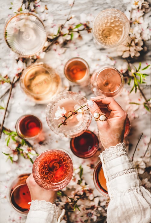 Preview: Womans hands over rose wine over white marble background