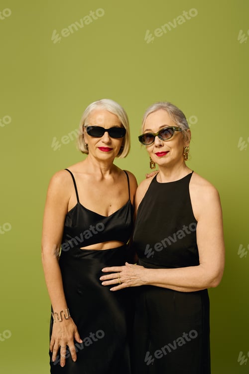 Preview: Fashionable mature lesbian couple posing against a vibrant green backdrop in stylish outfits