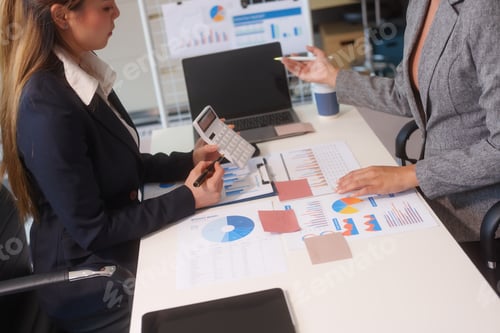 Preview: Close-up of two businesswomen working at desk discussing business strategies, analyzing financial
