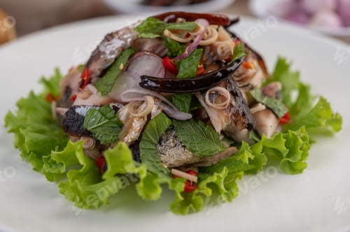 Preview: Deep-fried mackerel topped with galangal, pepper, mint, red onion in a white dish.