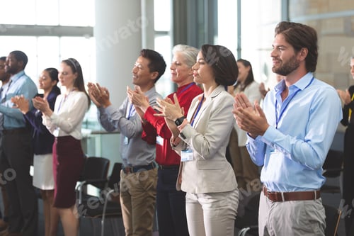 Preview: Side view of diverse business people applauding standing at a business seminar in office building