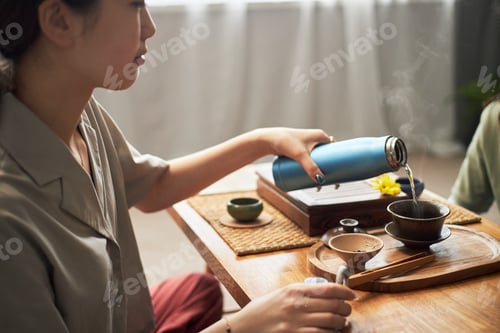 Preview: Young Asian Woman Pouring Hot Tea during Traditional Cultural Gathering