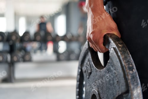 Preview: Close-up of a strong hand gripping a weight plate in a gym