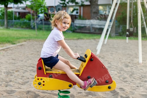 Preview: Little smiling girl playing at playground in summer. Small child having fun outdoors on sunny day