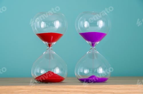 Preview: Two vibrant hourglasses on a wooden shelf are measuring the passage of time