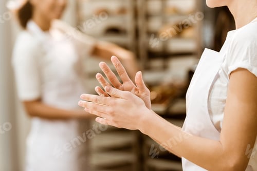 Preview: cropped shot of female baker with hands covered in flour at baking manufacture
