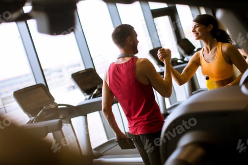 Preview: Young woman and personal trainer rest in the gym after workout