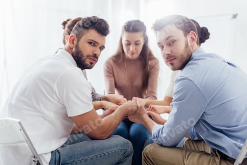 Preview: selective focus of group of people sitting and stacking hands during therapy session