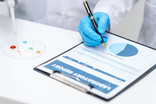 Preview: Two Asian scientists in lab coats sit at table in laboratory, examining samples through microscope