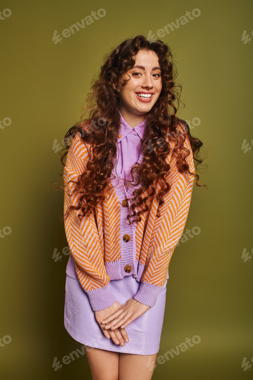 Preview: Stylish young woman smiling against a vibrant green backdrop showcasing her unique fashion sense