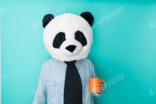 Preview: Person in panda mask holding a cup of coffee on colored background
