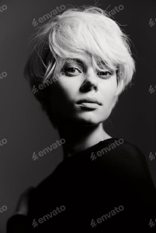 Preview: Confident young woman with short white hair posing in moody black and white lighting, showcasing a