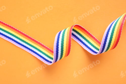 Preview: Bright rainbow ribbon on color background, top view. Symbol of gay community