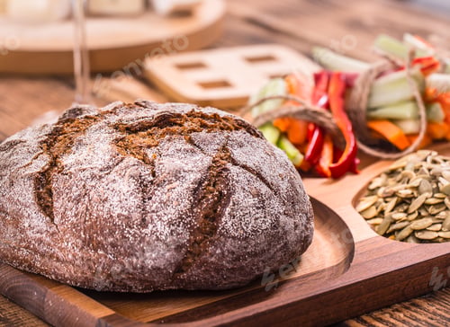 Preview: A fresh round of dark bread on a wooden plate