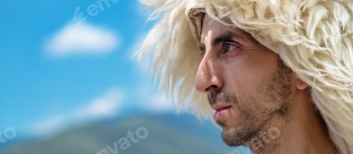Preview: A Georgian man in a hat against the background of mountains and the sky. Selective focus.