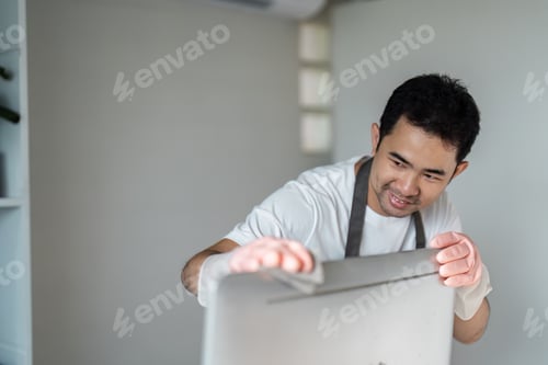 Preview: Man Cleaning a Computer Screen with a Cloth in a Modern Home Office Setting