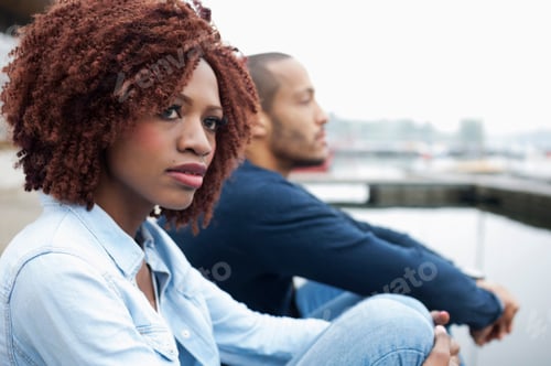 Preview: Couple sitting by the water, seemingly lost in thought