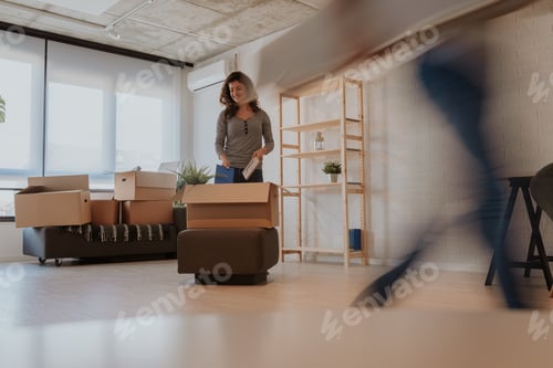 Preview: Photo of good looking brunette unpacking boxes on moving day. Young woman is moving in to new home.