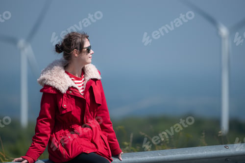 Preview: On the background of windmills, A young woman in a red jacket is enjoying her winter vacation.