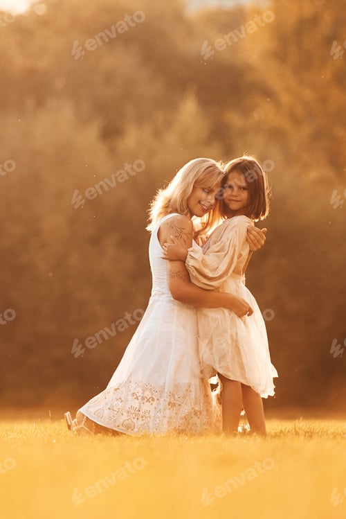 Preview: Embracing each other. Woman with her daughter is on the summer field
