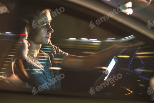 Preview: The man and woman sitting in the car and phone. evening night time