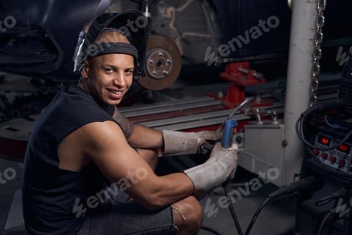 Preview: Confident Man Working on Car With Welding Equipment