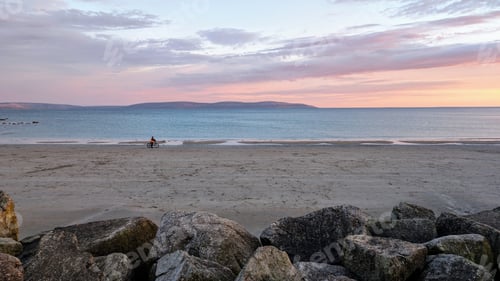 Preview: Silhouetted man riding bike on sandy beach at sunset, coastal landscape, Silverstrand, Galway, Irela