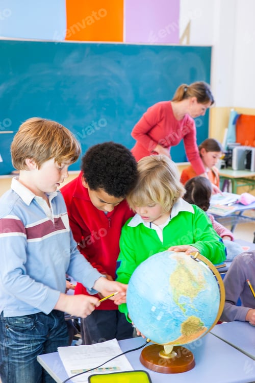 Preview: Primary schoolboys looking at globe in classroom