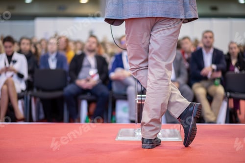 Preview: Unrecognizable businessman giving presentation to large group of people in convention center.