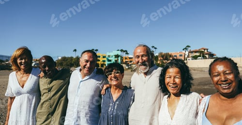 Preview: Happy senior people having fun walking on the beach at sunset wearing summer clothes