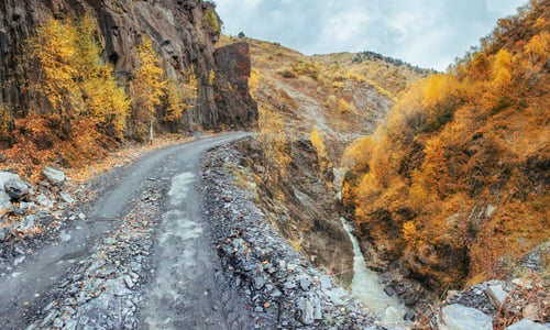 Preview: golden autumn landscape between the rocky mountains in Georgia. Stone road. Europe