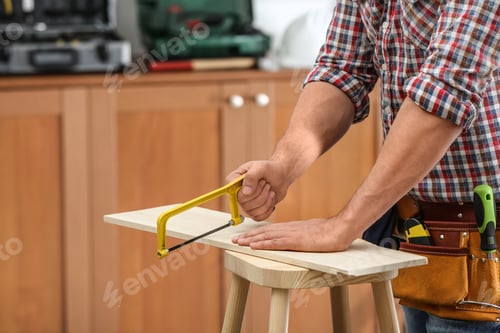 Preview: Man working with hand saw indoors, closeup. Home repair