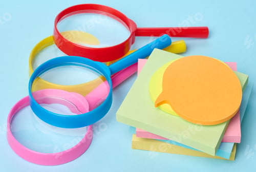 Preview: Multicolored plastic magnifying glasses on a blue background and paper notes