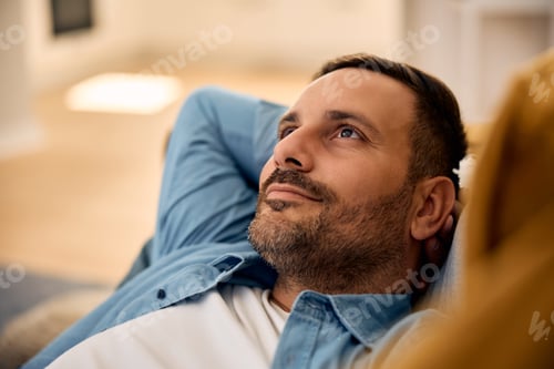 Preview: Pensive man day dreaming while relaxing at home.