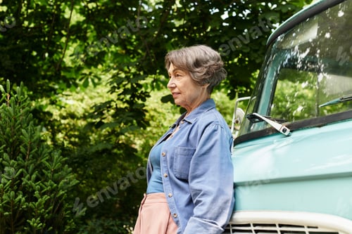 Preview: Elegant senior woman enjoying a serene moment in a vibrant garden filled with lush greenery